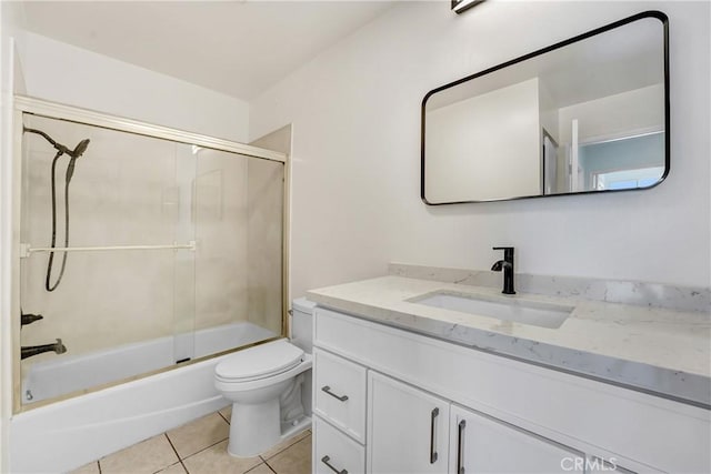bathroom featuring toilet, enclosed tub / shower combo, tile patterned flooring, and vanity