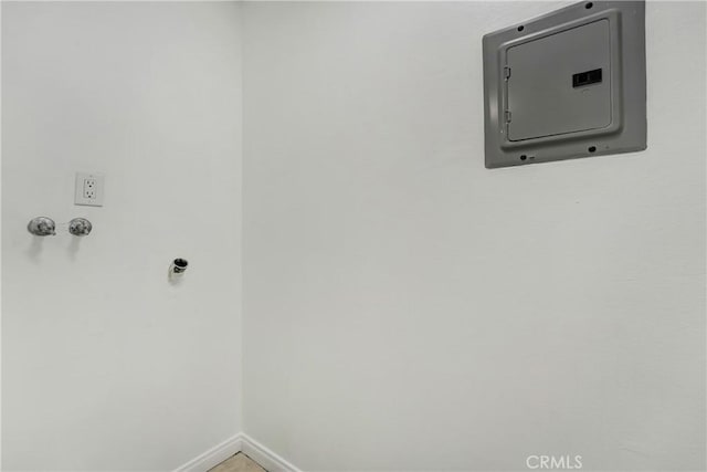 clothes washing area with electric panel and baseboards