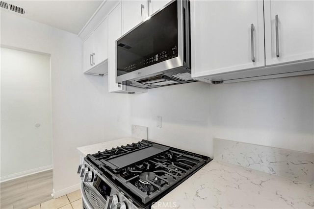 kitchen featuring light stone counters, visible vents, white cabinets, and appliances with stainless steel finishes