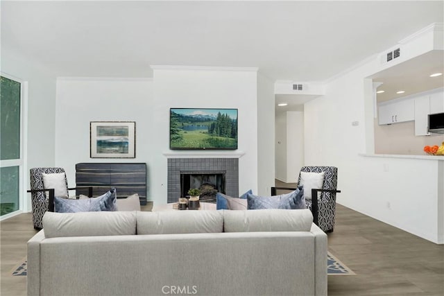 living room featuring a tile fireplace, visible vents, and wood finished floors
