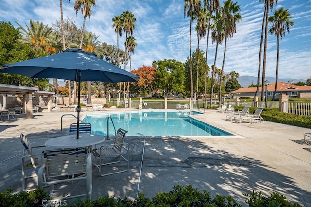 pool featuring a mountain view, a patio, and fence