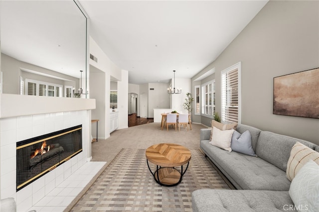 living area featuring carpet flooring, a notable chandelier, a tile fireplace, and visible vents