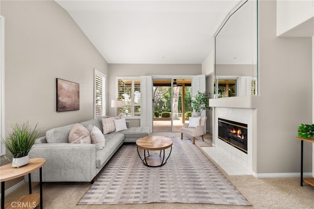 living area with baseboards, a fireplace, carpet, and vaulted ceiling