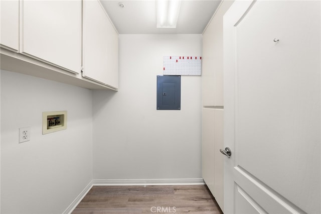 clothes washing area with electric panel, cabinet space, wood finished floors, baseboards, and hookup for a washing machine