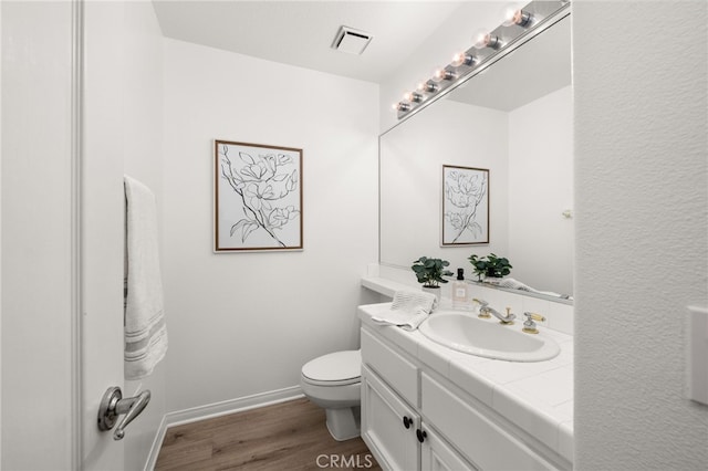 bathroom featuring toilet, baseboards, visible vents, vanity, and wood finished floors