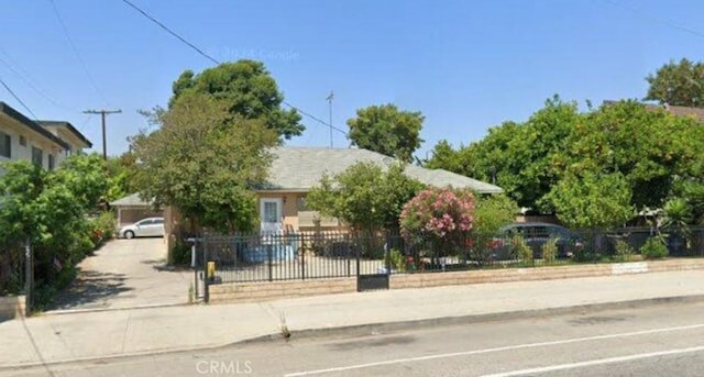 obstructed view of property featuring a fenced front yard and concrete driveway