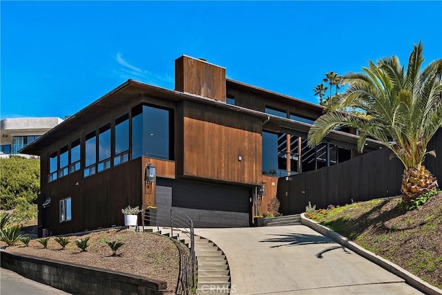 view of front facade with concrete driveway, an attached garage, and fence