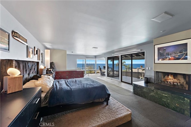 bedroom with a lit fireplace, carpet, and access to exterior