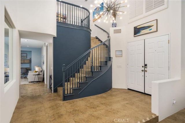 entryway featuring an inviting chandelier, stairs, a high ceiling, and visible vents