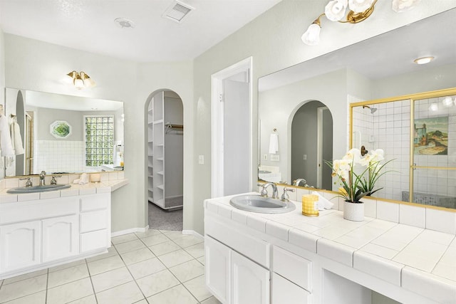 bathroom with vanity, visible vents, tile patterned floors, a shower stall, and a walk in closet