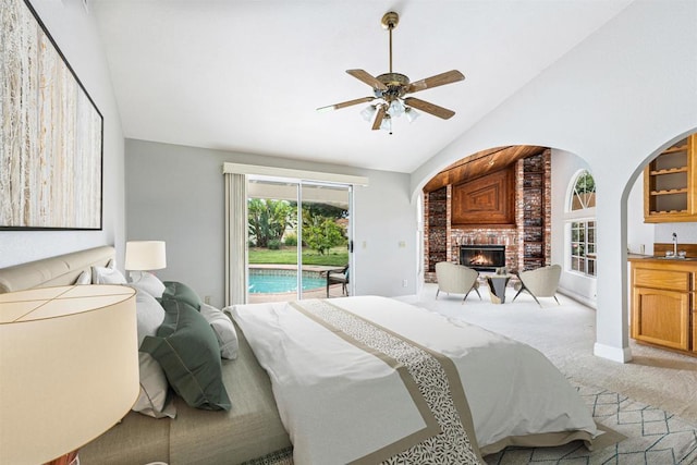 bedroom featuring light colored carpet, high vaulted ceiling, a brick fireplace, a ceiling fan, and access to outside