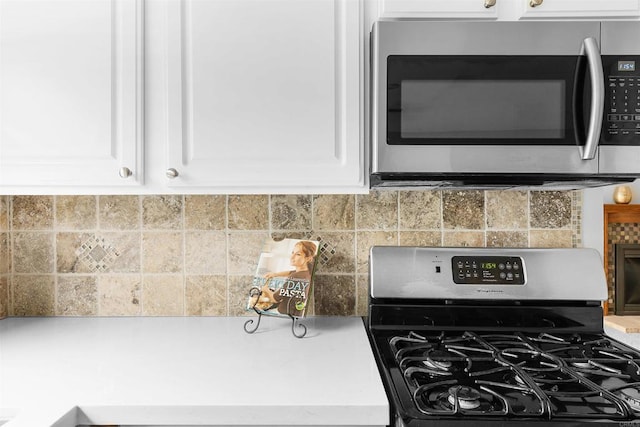 kitchen with decorative backsplash, white cabinets, and appliances with stainless steel finishes