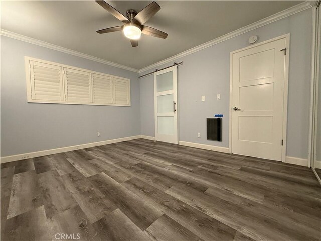 unfurnished bedroom featuring crown molding, a barn door, baseboards, and dark wood-style floors