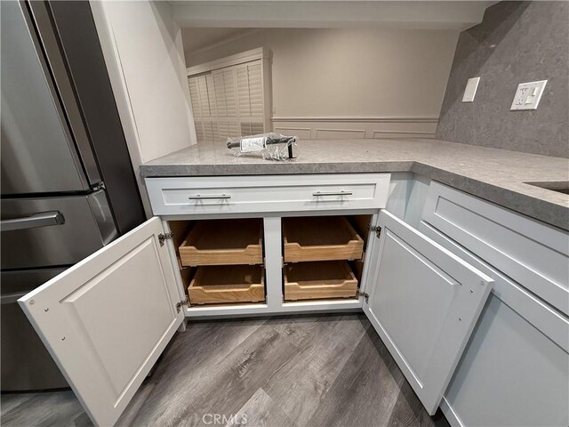 details with stainless steel refrigerator, white cabinetry, light countertops, and dark wood finished floors