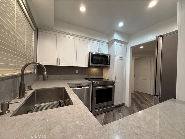 kitchen featuring a sink, dark wood finished floors, recessed lighting, white cabinets, and appliances with stainless steel finishes
