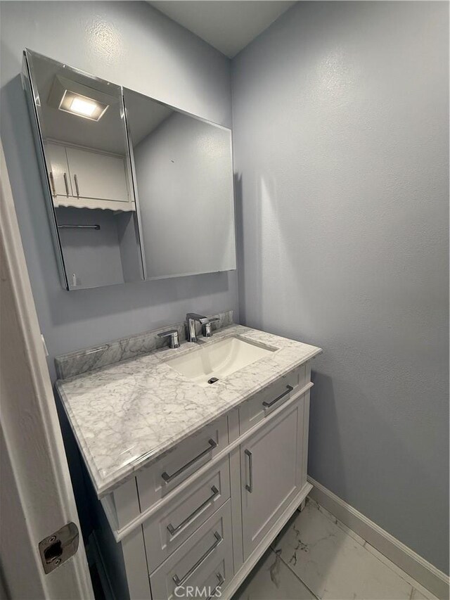 bathroom featuring baseboards, marble finish floor, and vanity