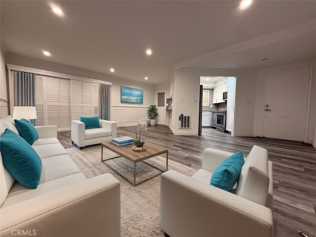 living room featuring wood finished floors, ornamental molding, visible vents, recessed lighting, and baseboards