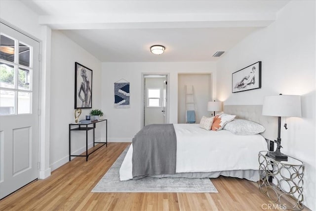 bedroom featuring multiple windows, visible vents, wood finished floors, and beamed ceiling