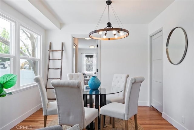 dining space with an inviting chandelier, baseboards, and light wood-type flooring