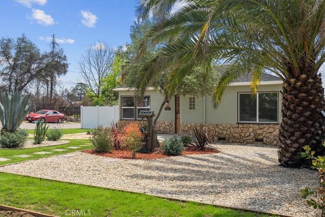 exterior space with fence, stucco siding, and stone siding