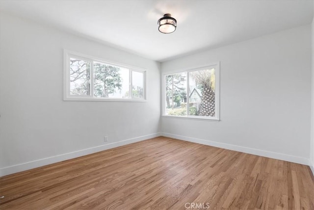 spare room with baseboards and light wood-type flooring