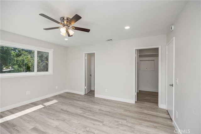 unfurnished bedroom featuring a spacious closet, baseboards, light wood-type flooring, and visible vents