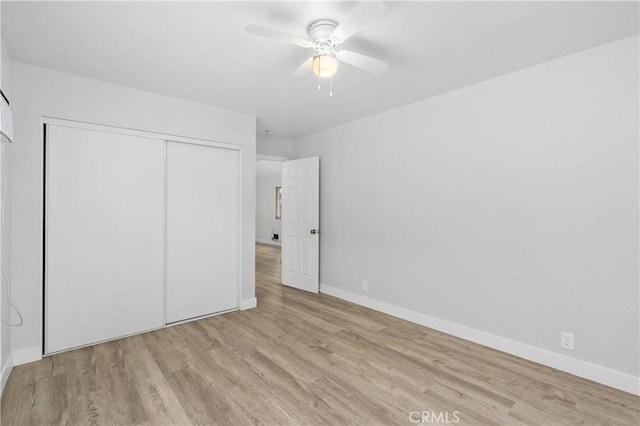 unfurnished bedroom with a closet, wood finished floors, and baseboards
