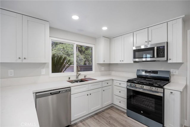kitchen with white cabinets, light countertops, stainless steel appliances, and a sink