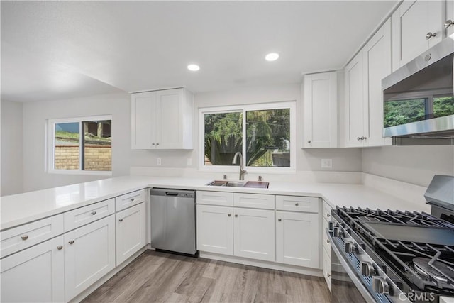kitchen featuring a sink, white cabinetry, plenty of natural light, and appliances with stainless steel finishes