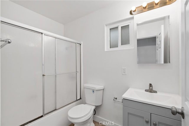 bathroom featuring toilet, baseboards, vanity, and combined bath / shower with glass door