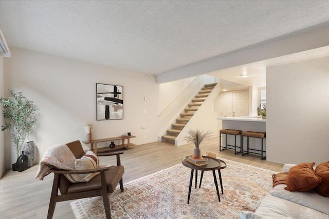 living area featuring stairs, light wood-type flooring, and a textured ceiling