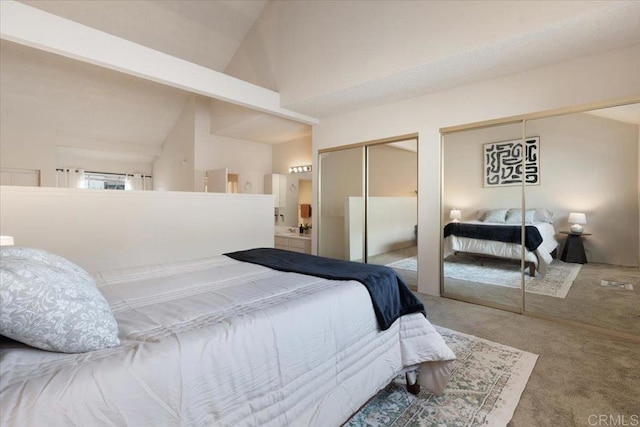 carpeted bedroom featuring two closets and high vaulted ceiling