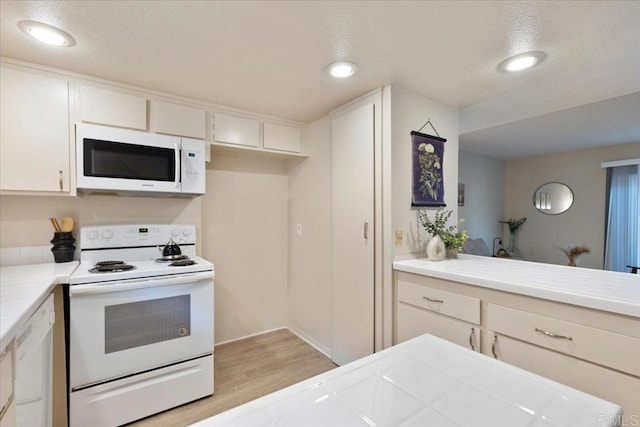kitchen with white appliances, light countertops, light wood-type flooring, and a textured ceiling