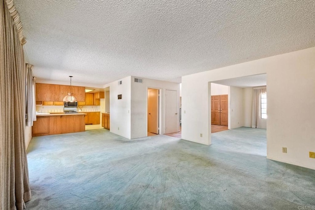 unfurnished living room featuring light colored carpet, a textured ceiling, and visible vents