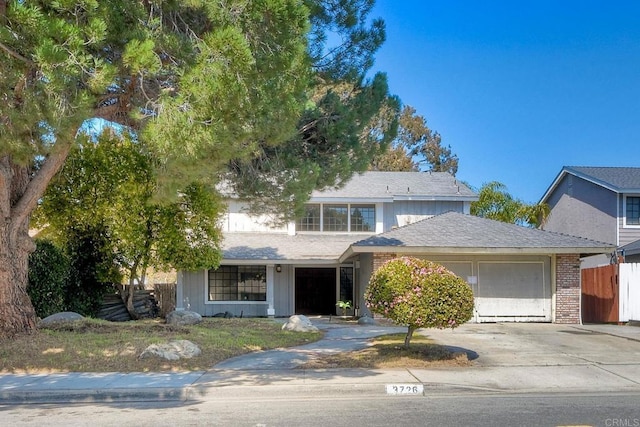 traditional home featuring concrete driveway, brick siding, fence, and a garage