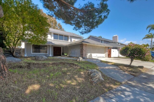 traditional home featuring concrete driveway, a garage, fence, and brick siding