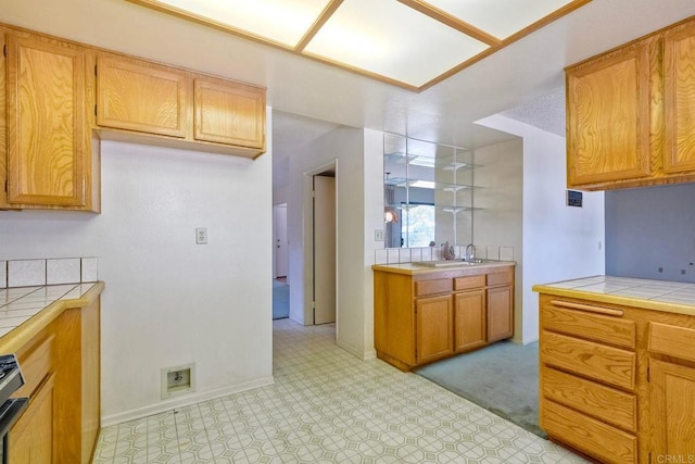 kitchen with brown cabinetry, tile counters, baseboards, and light floors