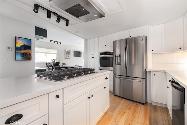 1145 Apache, Topanga, CA 90290 - kitchen featuring appliances with stainless steel finishes, light wood finished floors, light countertops, white cabinets, and backsplash