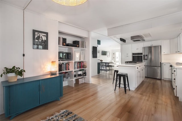 1145 Apache, Topanga, CA 90290 - kitchen featuring appliances with stainless steel finishes, light wood finished floors, a breakfast bar area, white cabinets, and a kitchen island