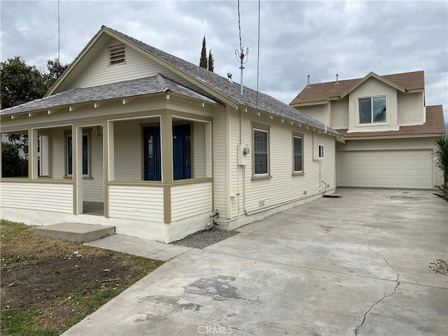 view of front of home with covered porch, roof with shingles, concrete driveway, and a garage