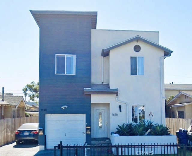 view of front facade featuring concrete driveway, stucco siding, a fenced front yard, and an attached garage
