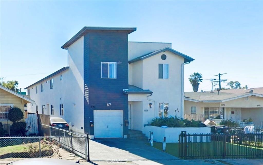 view of front of home with concrete driveway, a fenced front yard, stucco siding, and an attached garage