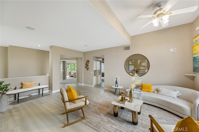 living area featuring visible vents, light wood-style flooring, baseboards, and ceiling fan
