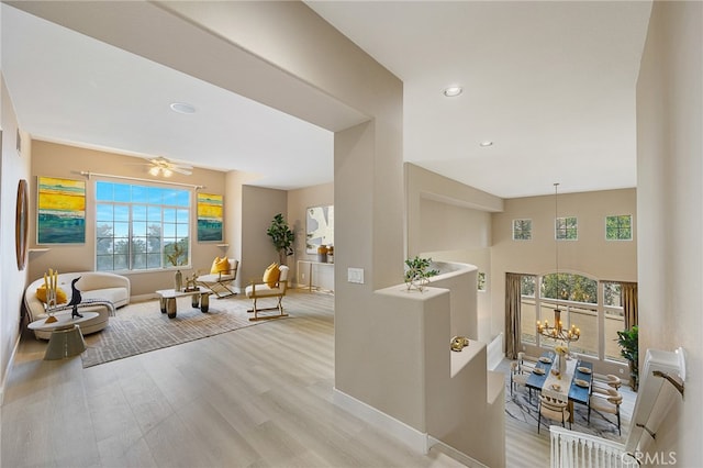 hall with baseboards, a wealth of natural light, a chandelier, and wood finished floors