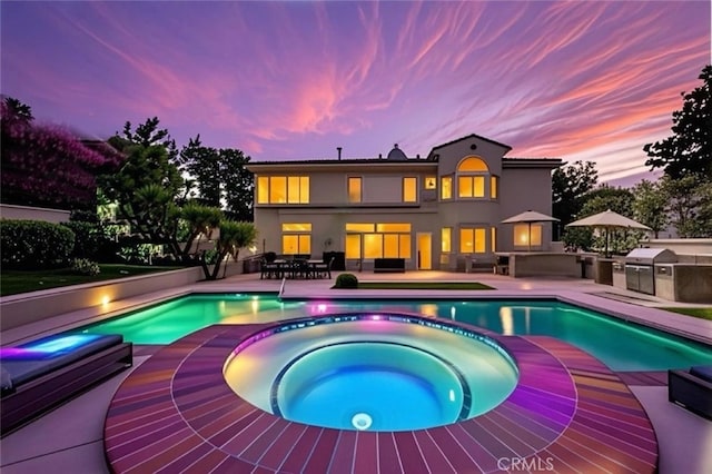 pool at dusk with a pool with connected hot tub, a patio area, area for grilling, outdoor dining space, and grilling area