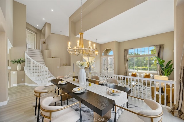 dining room with wood finished floors, baseboards, stairway, a high ceiling, and a notable chandelier
