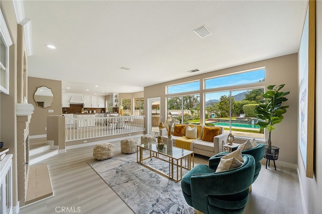 living area with baseboards, light wood-style floors, and visible vents