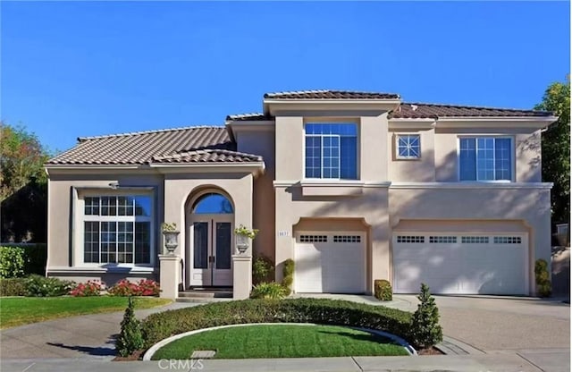 view of front of house with driveway, stucco siding, an attached garage, and a tile roof