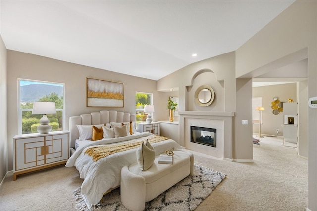 bedroom with lofted ceiling, carpet, baseboards, and a glass covered fireplace