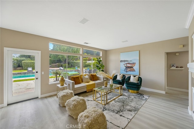 living area featuring baseboards, light wood finished floors, and visible vents